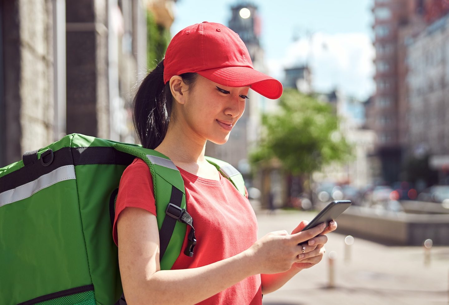 Asian student delivering food through city using mobile phone